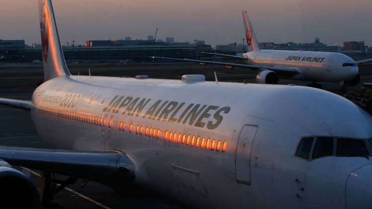 A Japan Airlines (JAL) aircraft is silhouetted against the setting sun as it lands at Haneda airport.