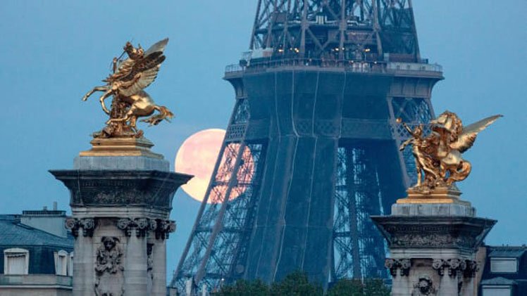 A supermoon sets behind the Eiffel Tower in Paris on April 27, 2021. France has also eased restrictions for some overseas visitors.