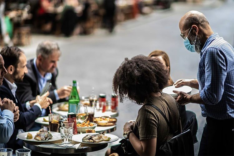 A waiter serves customers at a terrace of a restaurant in Paris as cafes and restaurants are allowed to serve customers inside, as well as on terraces. © Martin BUREAU/AFP via Getty Images
